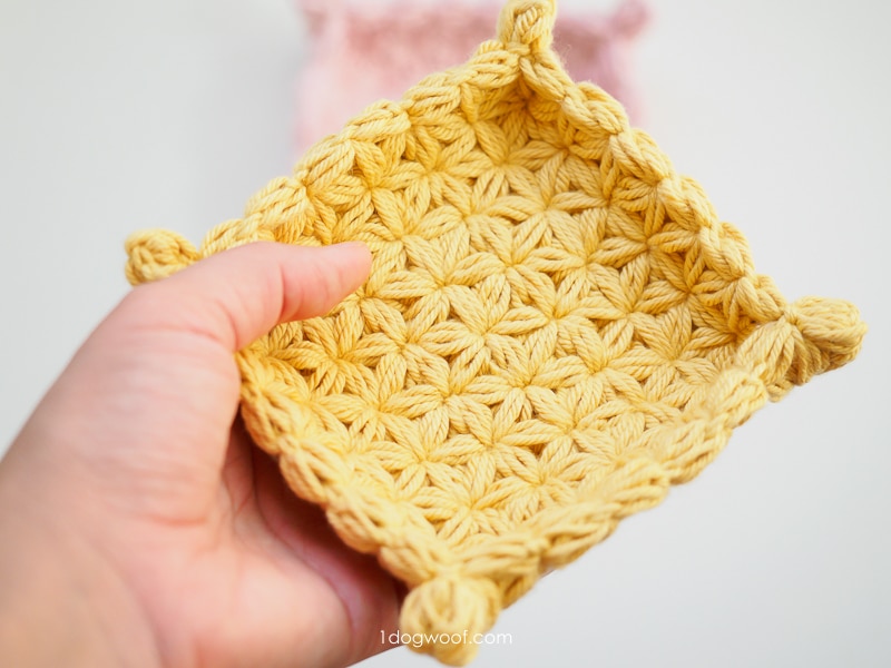holding a small yellow crochet jewelry dish